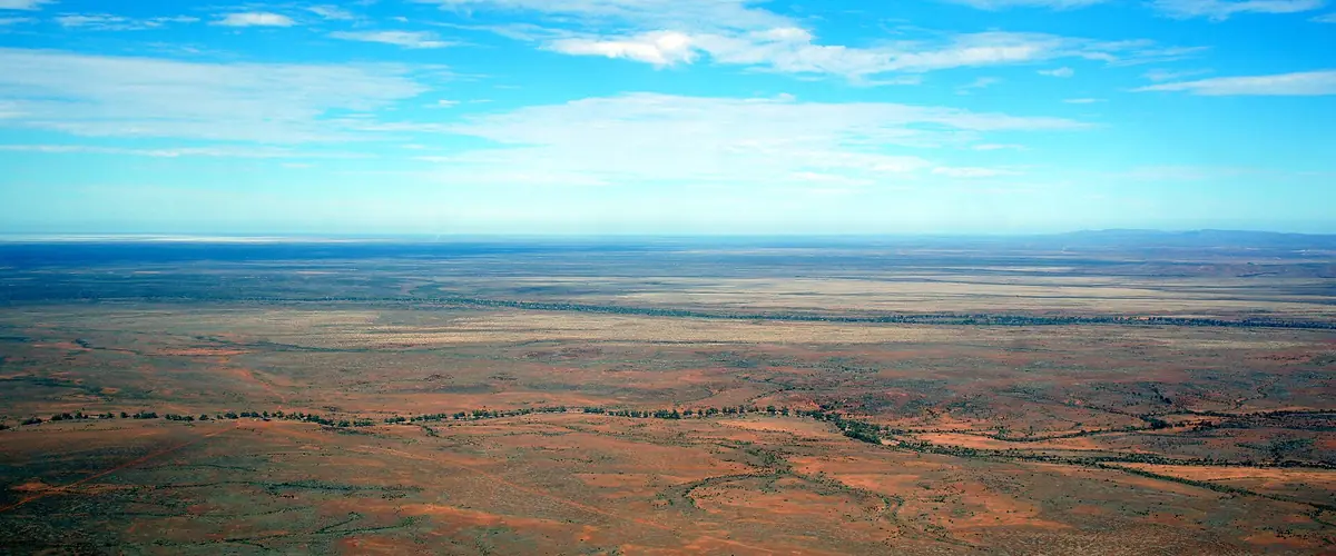 Wide view of red desert plain in outback South Australia under a pale blue sky
